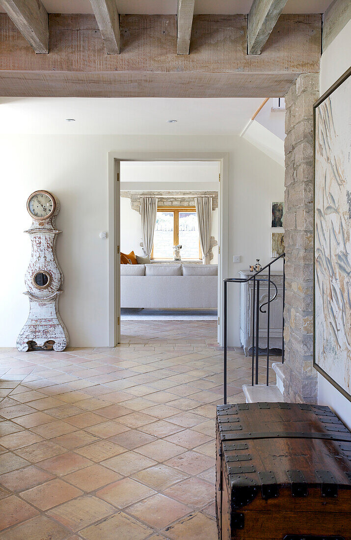 Hallway with terracotta tiles, wooden chest and antique grandfather clock