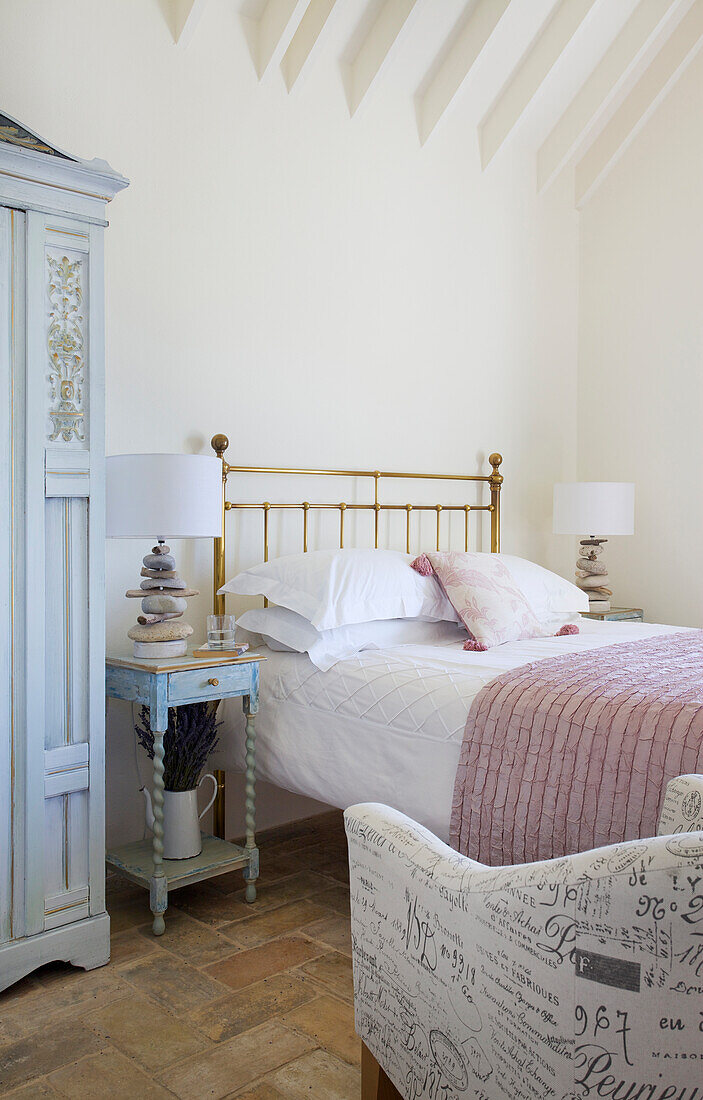 Brass bed and bedside table in the bright bedroom with lettering bedspread