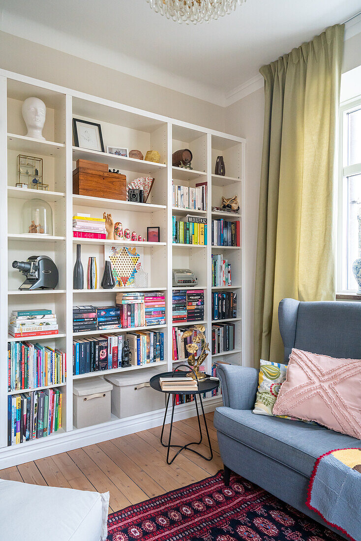 Wohnzimmer mit Bücherregal, blaugrauem Sofa und orientalischem Teppich