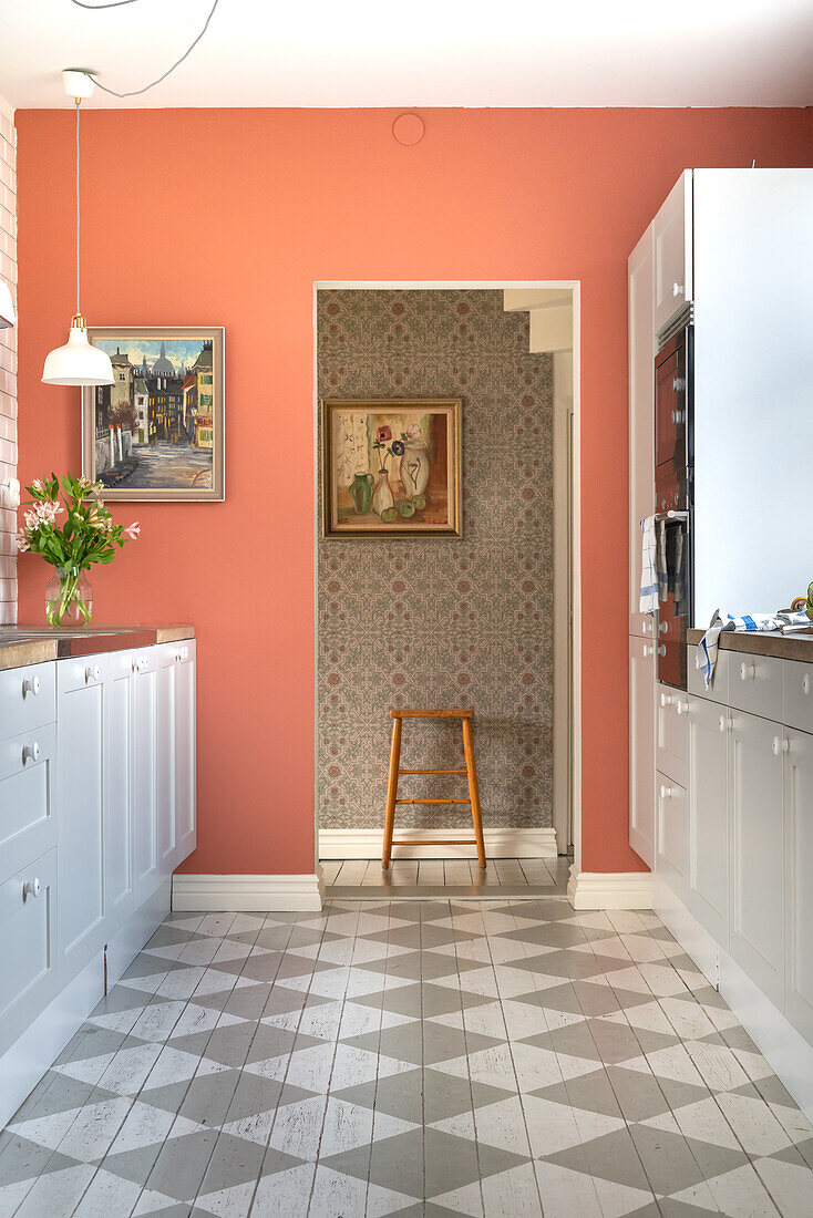 Kitchen with terracotta-coloured walls and chequerboard-look floor