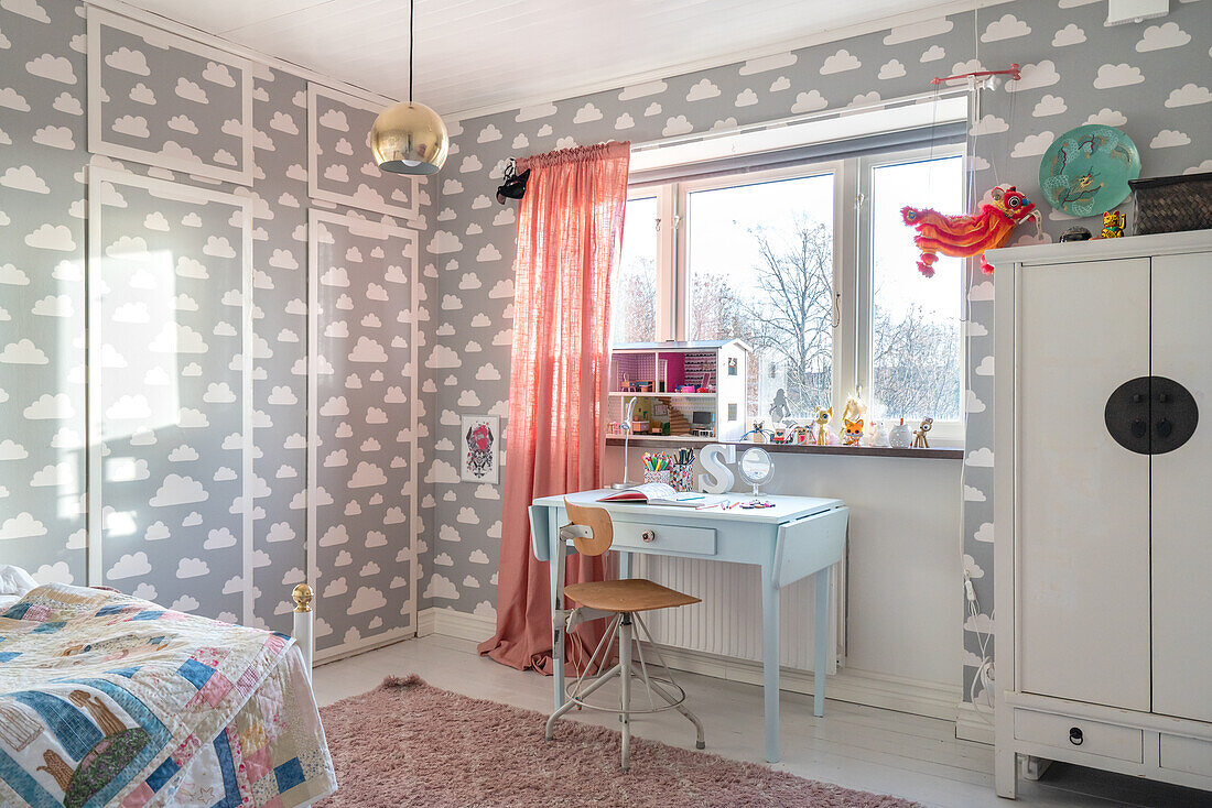 Children's room with cloud pattern wallpaper and colourful decorative elements