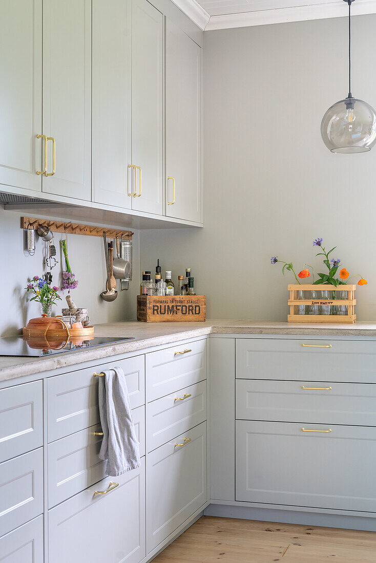 Light grey kitchen cabinets and decorative floral arrangement on worktop