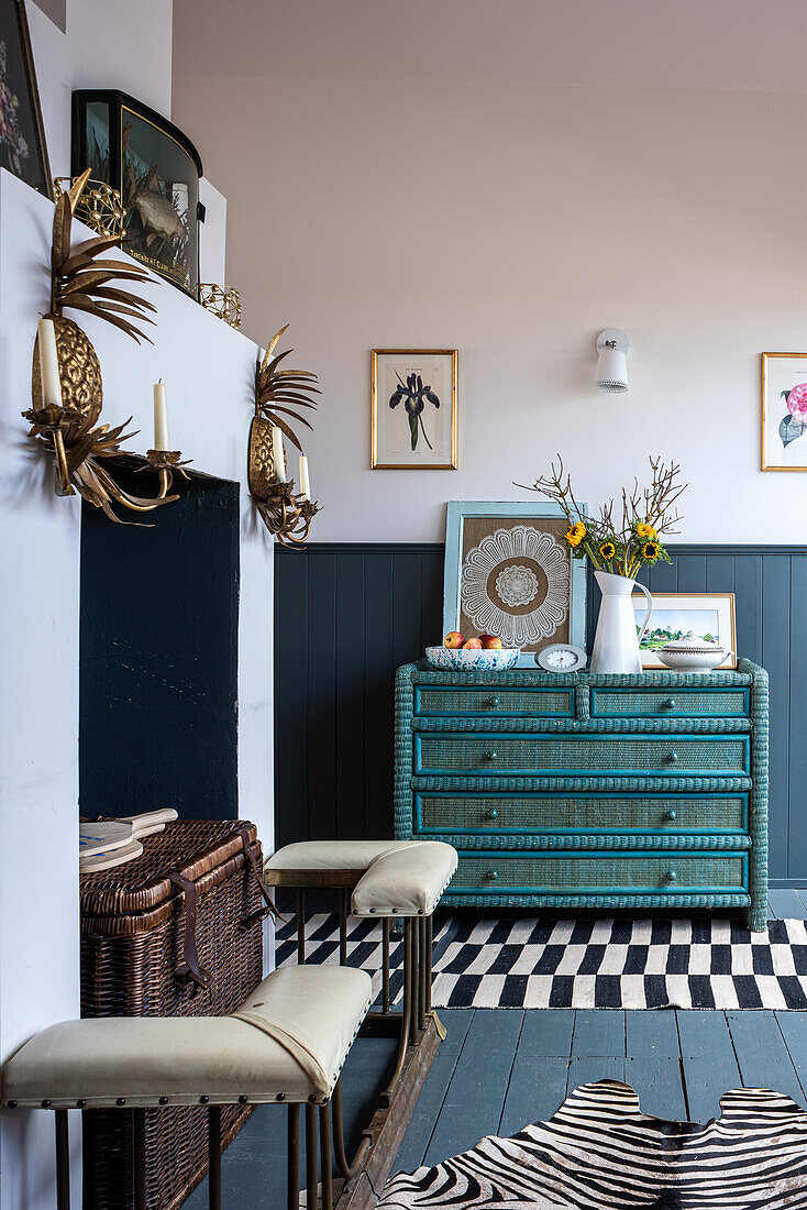 Vintage-style chest of drawers with vase of flowers and pineapple-shaped wall candle holders