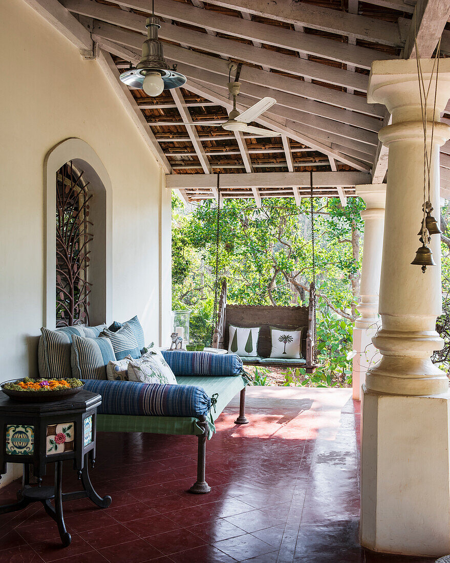 Veranda with bench, cushions with plant decor and hanging swing