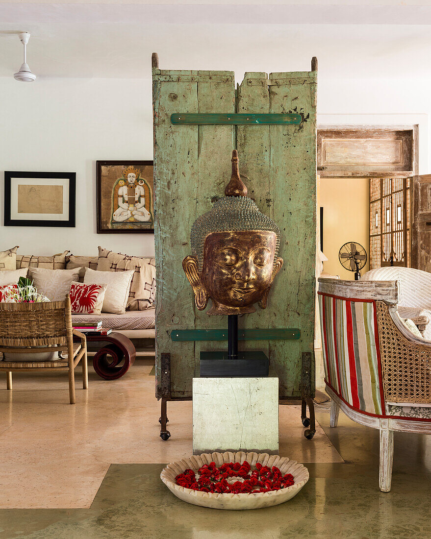 Antique wooden panel with Buddha head in exotically decorated room