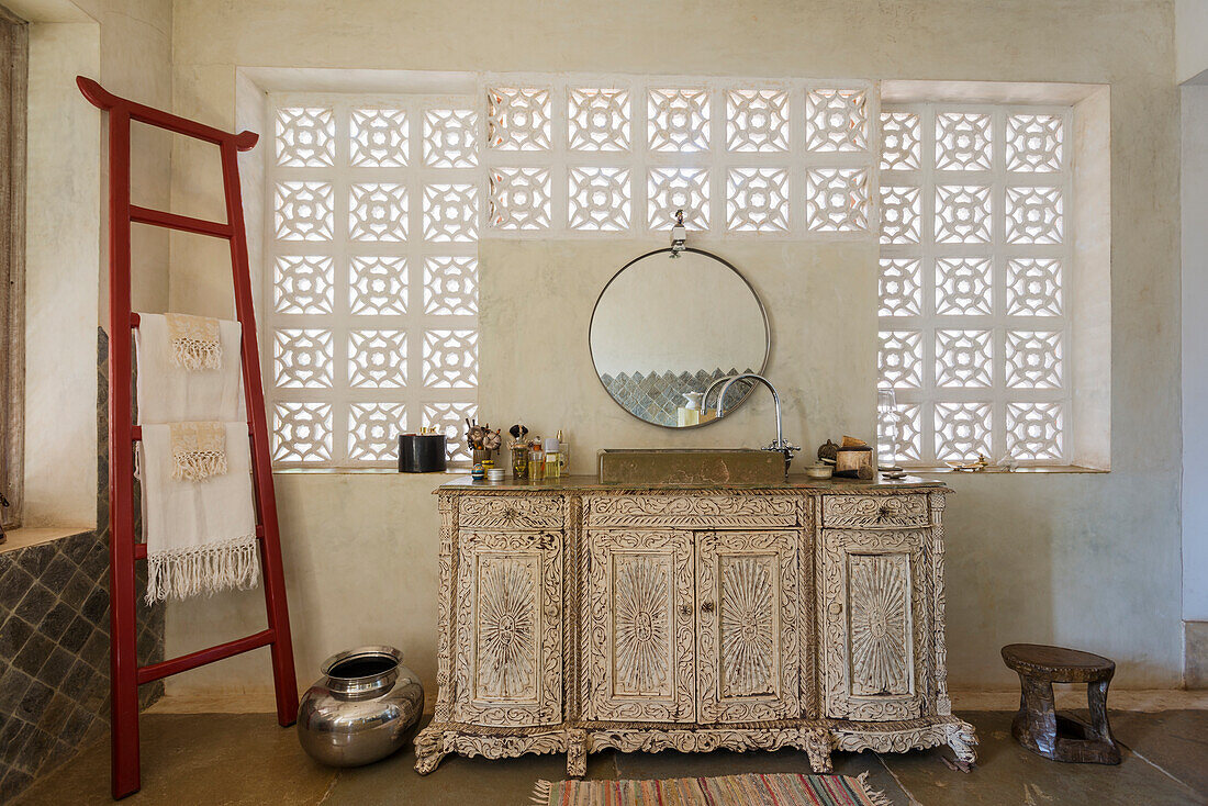 Bathroom with carved wooden washbasin and decorative window squares