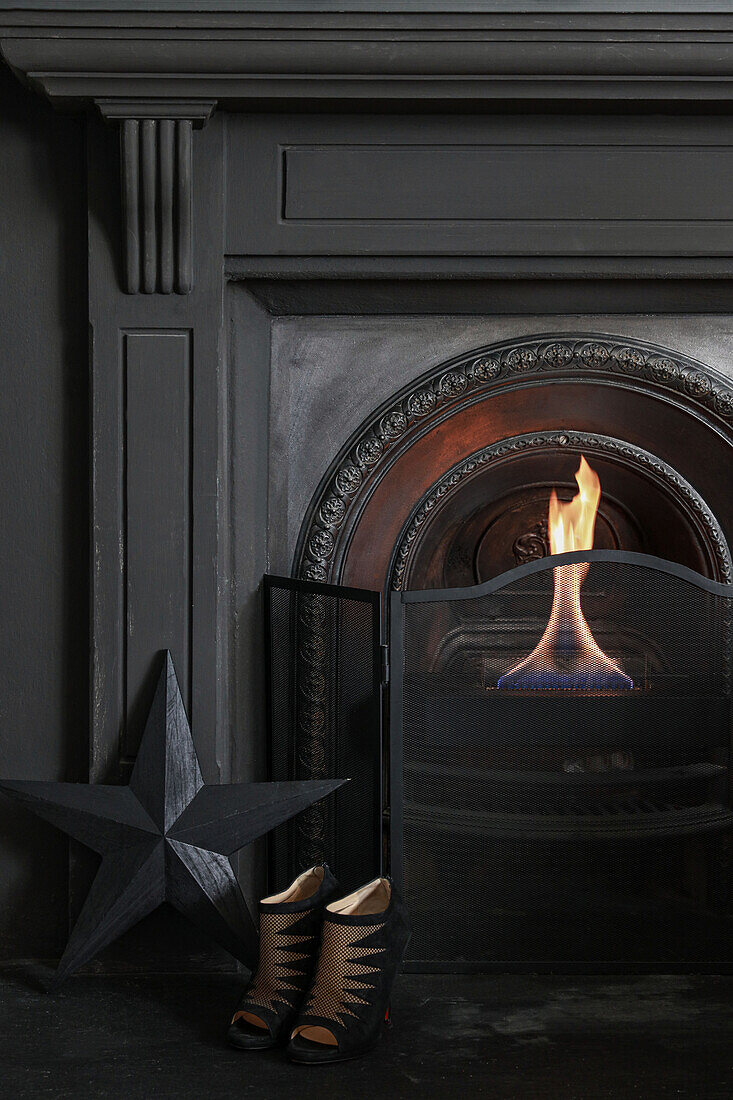 Highheels and black star in front of open fireplace with fire