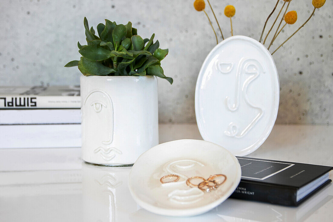 Ceramic dish and flower pots with abstract faces on a white table