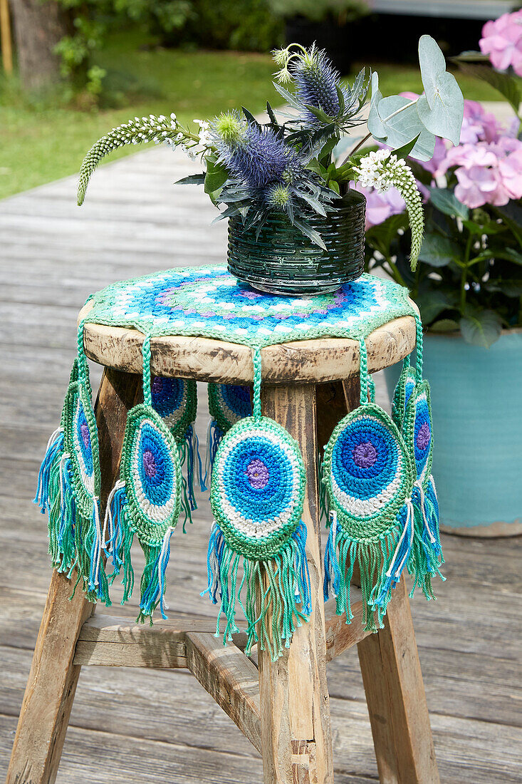 Wooden stool with crocheted peacock feather blanket