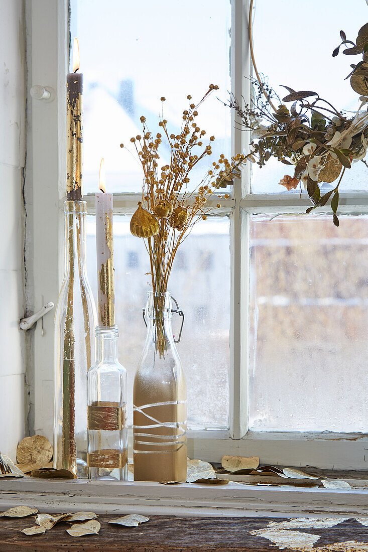 Trockenblumen in Glasflaschen auf Fensterbank