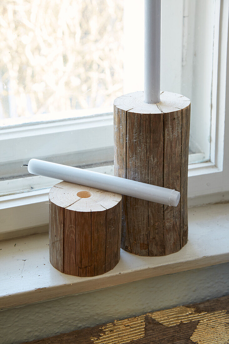 Candle holder made from logs on a windowsill with a view outside