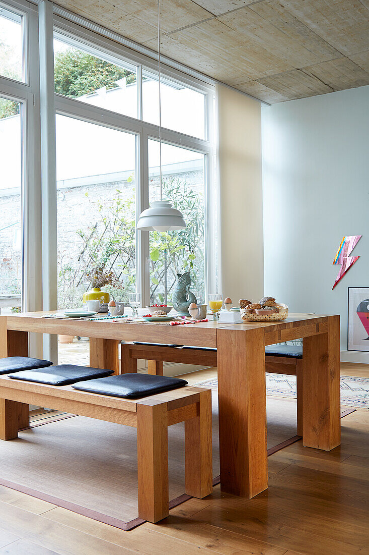 Solid wood table with benches and pendant light in light-colored dining room