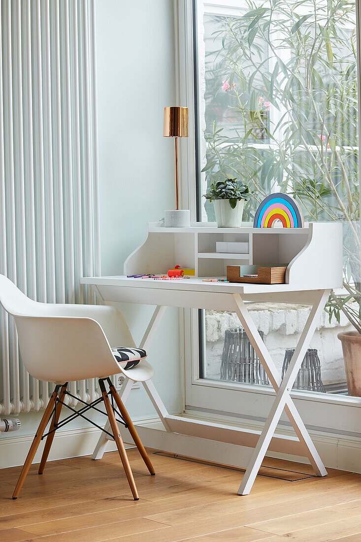 Small desk with shell chair in front of patio door