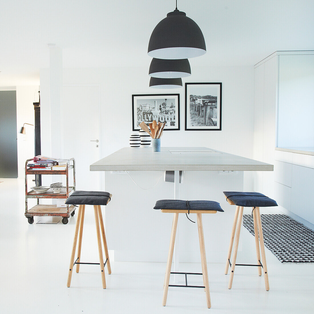 Minimalist kitchen island with bar stools and black pendant lights