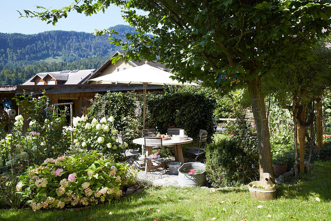 Idyllic garden with seating area and flowering beds in summer