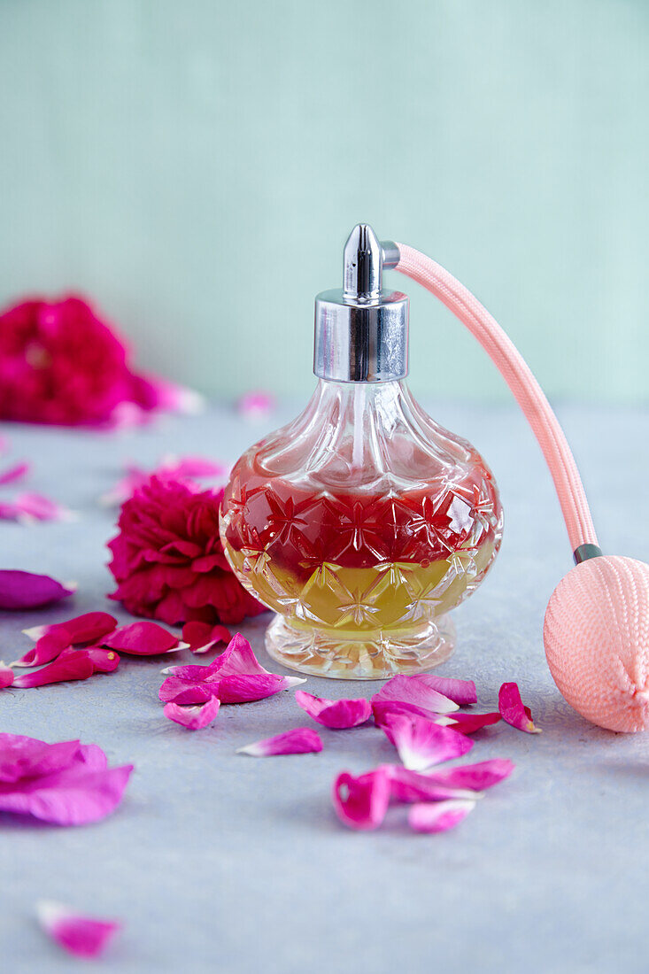 A shaking lotion (oil and hydrolate) in a bottle with a spray pump surrounded by rose petals