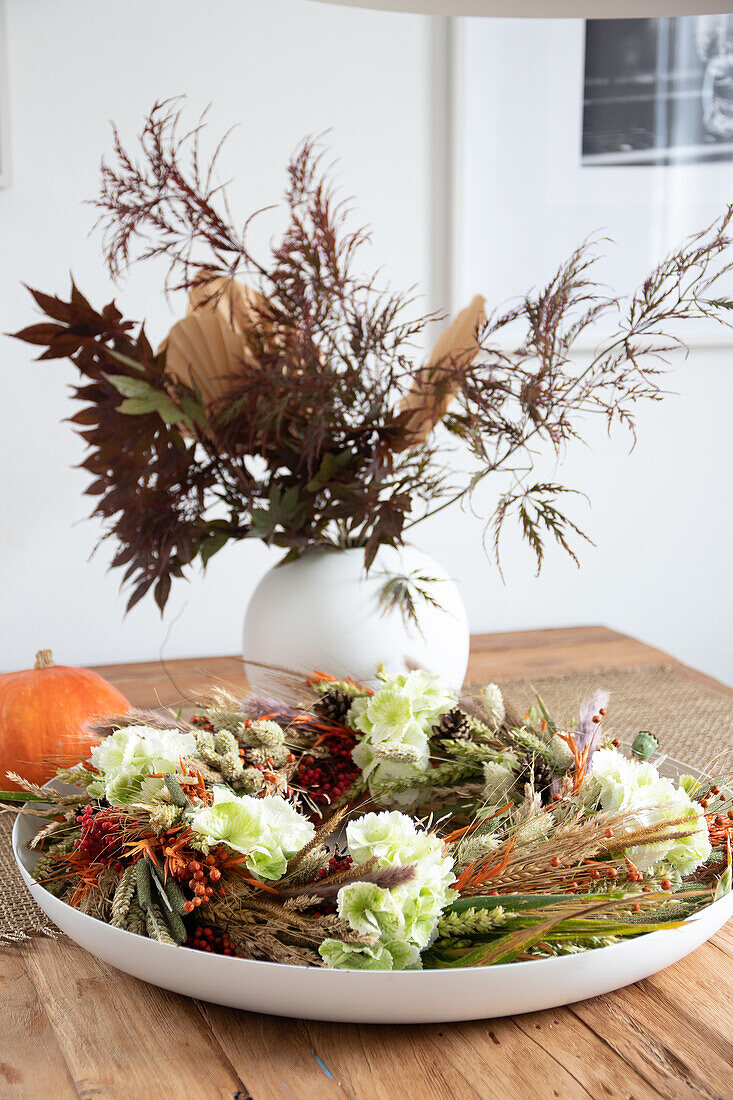 Autumn flower arrangement and DIY wreath on wooden table