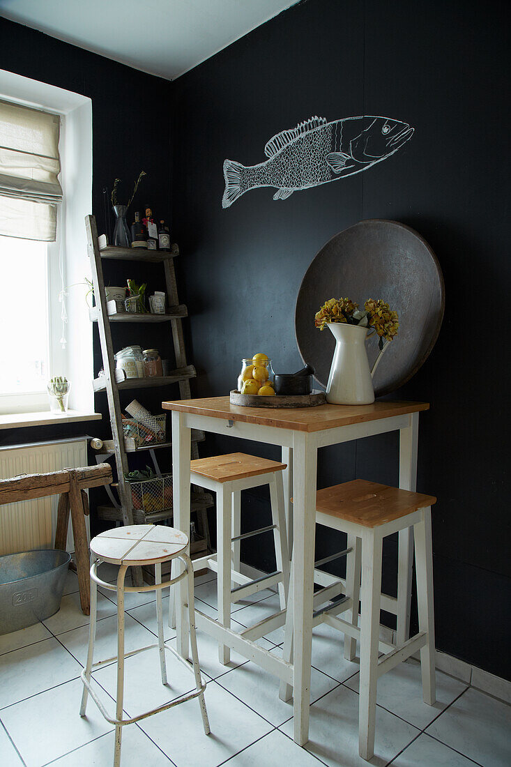 Bar height table with stools in kitchen with black walls and fish decor