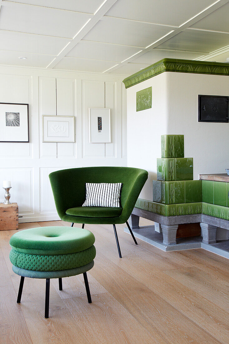 Green armchair with patterned cushion, matching stool and tiled stove