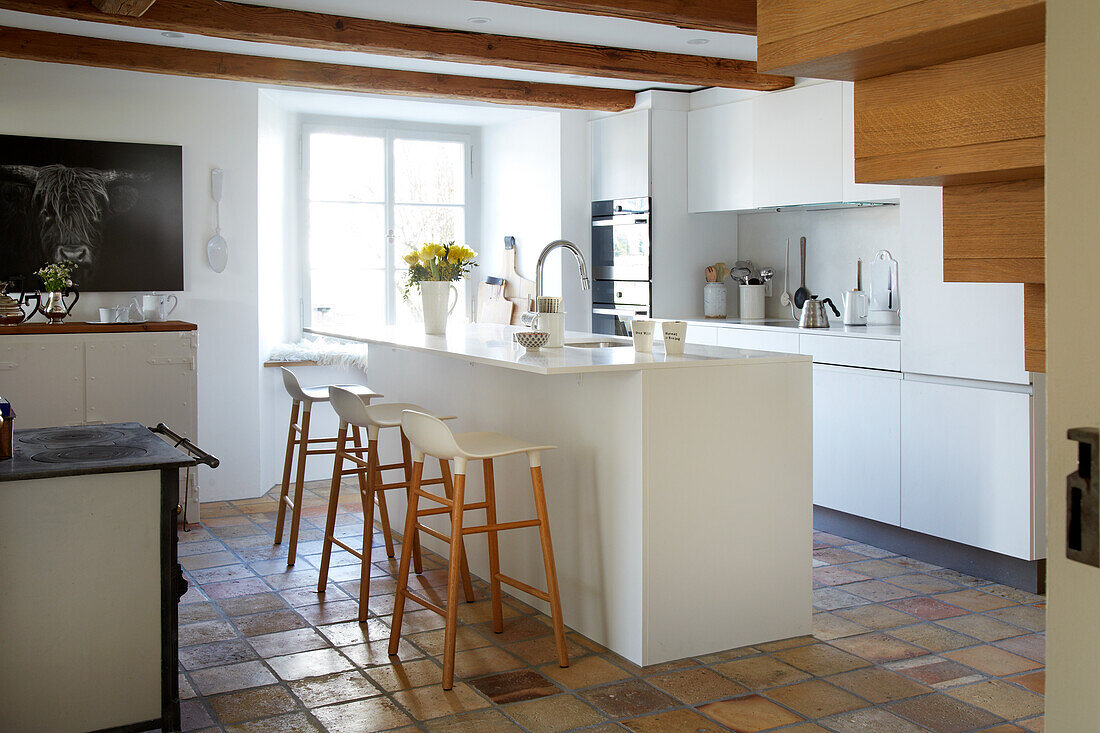 White kitchen island with yellow tulips and bar stools