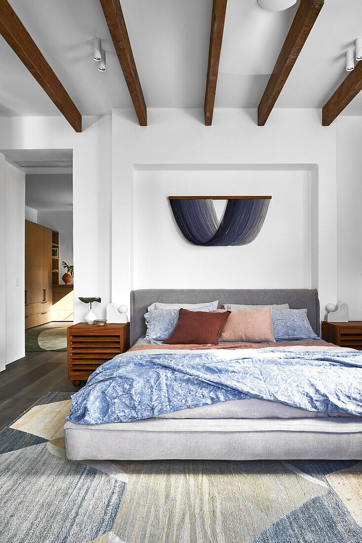 Bed in white bedroom with wooden beams