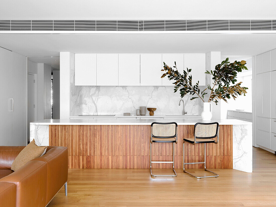 Marmor-Kücheninsel mit Klassiker-Barhockern in hellem, offenem Wohnraum
