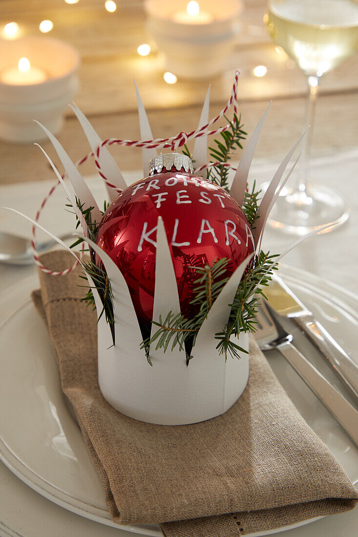 Christmas bauble as place card on plate with cloth napkin