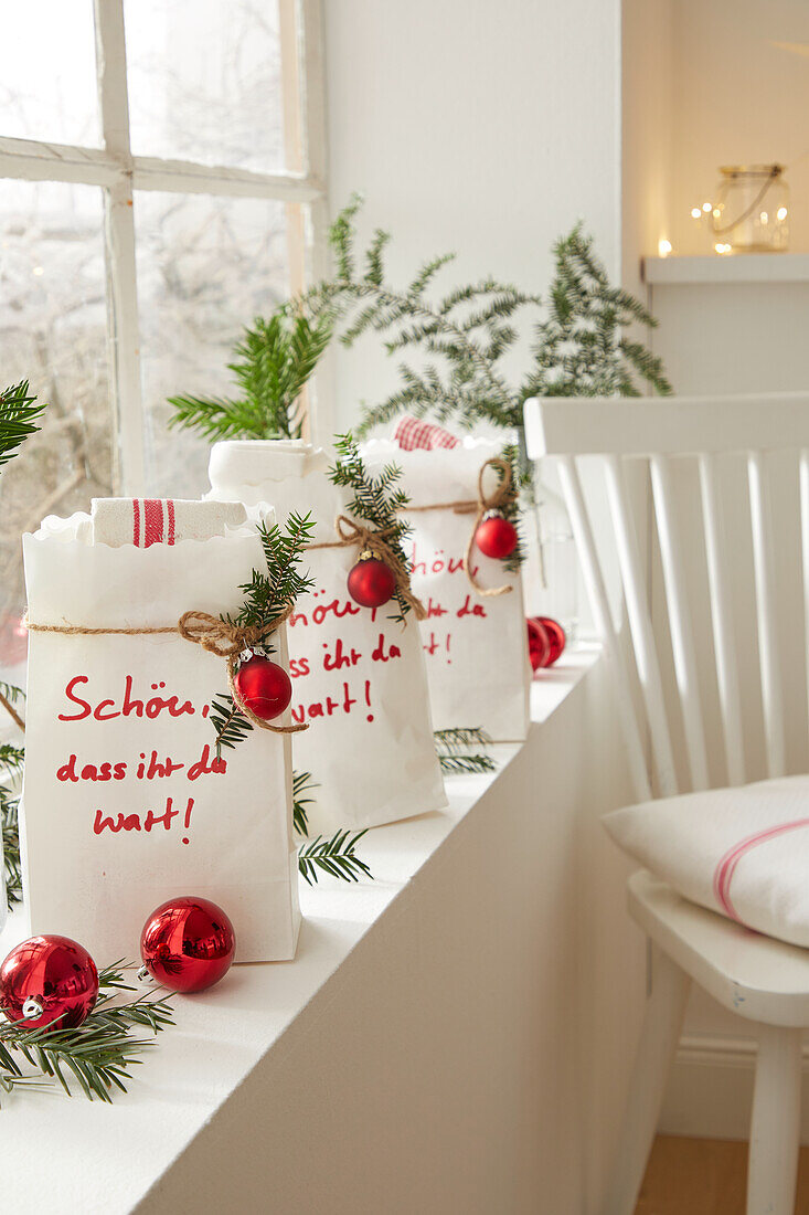 Windowsill decorated for Christmas with gift bags and red baubles