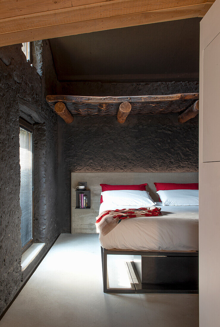 Bedroom with rustic stone wall and wooden beams
