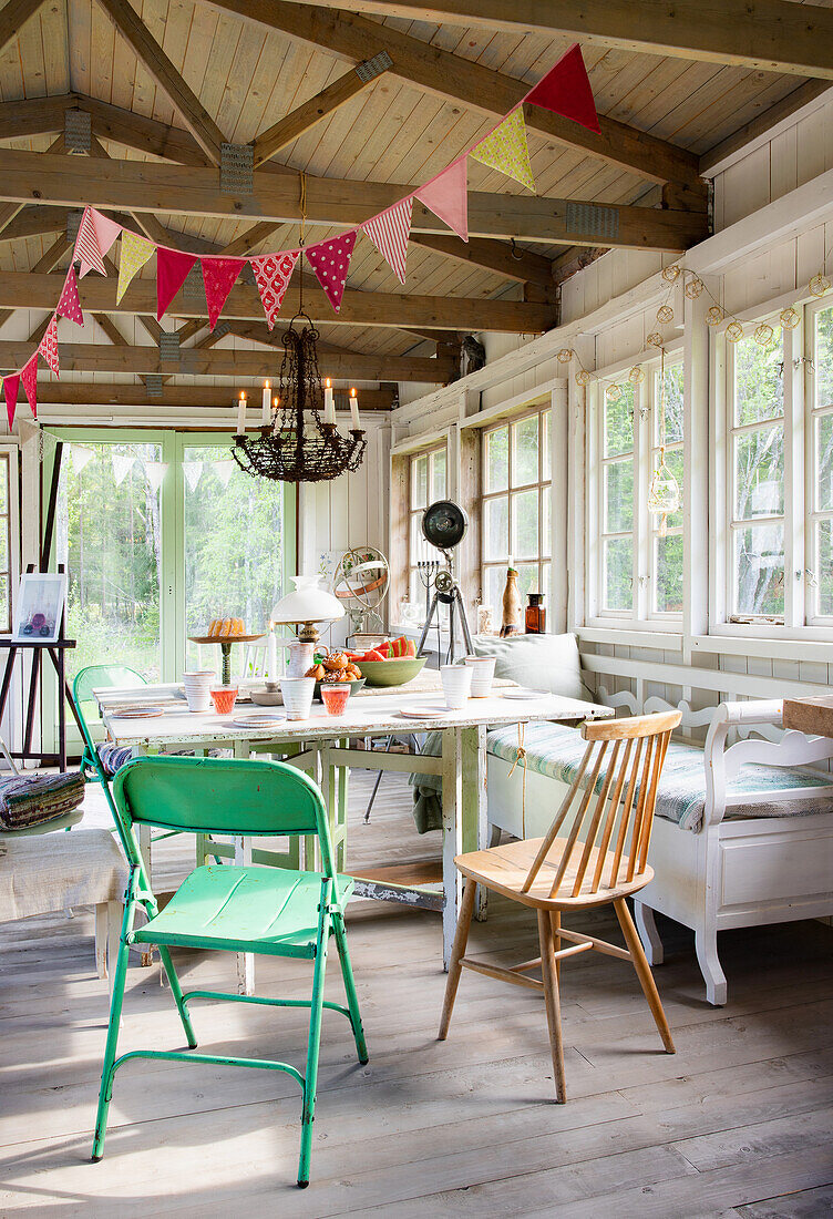 Bright garden house in rustic style with pennant chain, chandelier, table, kitchen bench and chairs