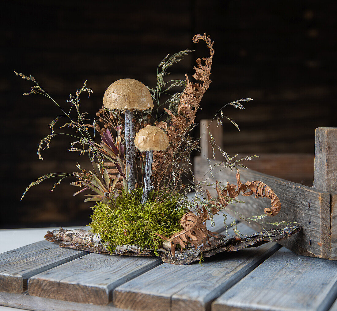 Autumnal arrangement with mushrooms and dried plants on a wooden table
