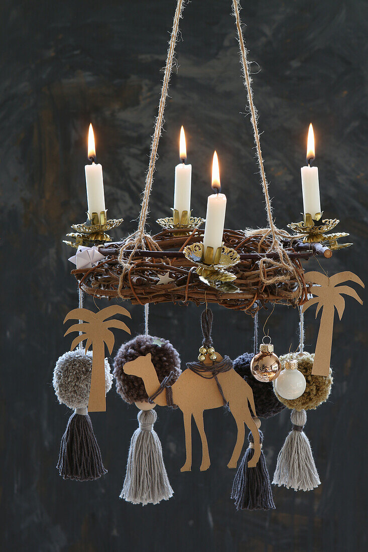 Hängender DIY-Adventskranz mit vier brennenden Kerzen und einem Kamel mit Palmen