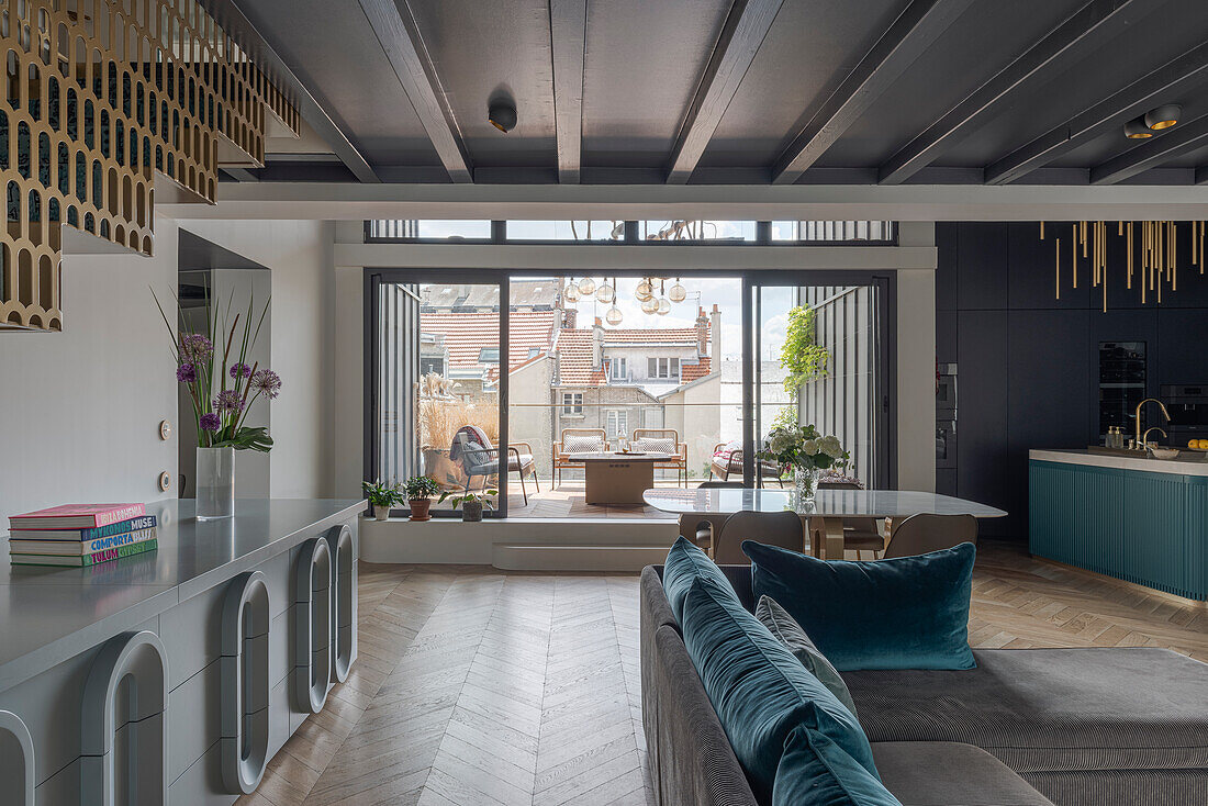 Graues Sideboard mit Art Deco Inspiration und graues Polstersofa mit blauen Kissen in offenem Wohnraum