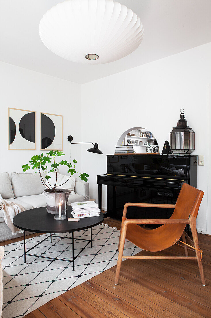 A leather chair, a piano, a light upholstered sofa and a black coffee table in a living room