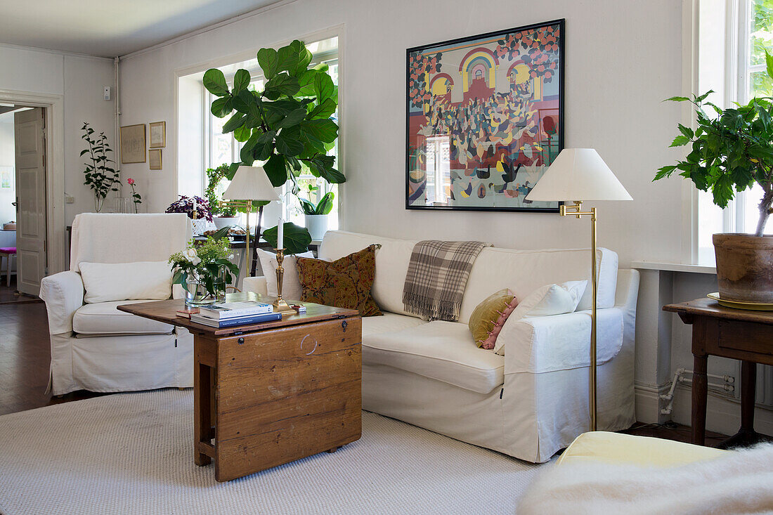 Wohnzimmer mit Hussenmöbeln, klappbarem Couchtisch und Zimmerpflanze