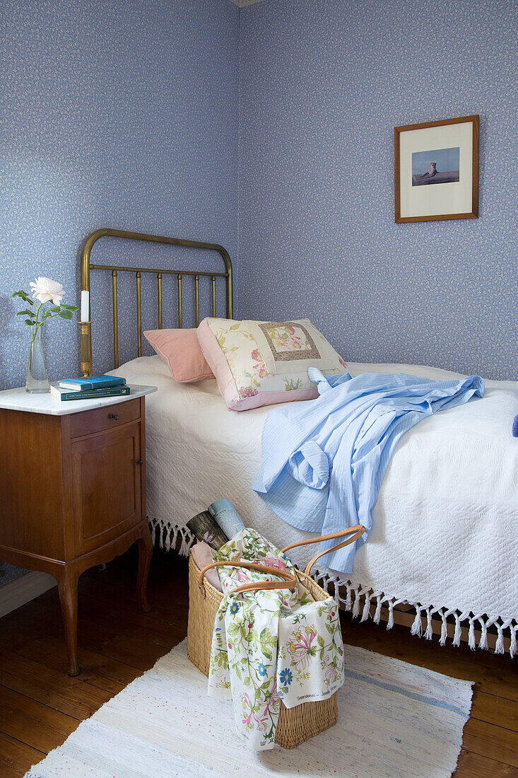 Brass bed and antique nightstand in a guest room with blue walls