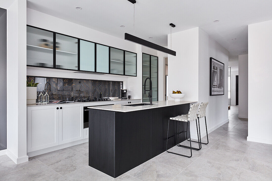 Moderne offene Küche mit weißen Unterschränken, Hängeschränken mit Glasfronten und schwarzer Kücheninsel