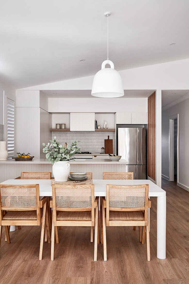 Offene Küche und Essbereich im modernen Scandi-Stil mit weißen Möbeln und Flechtstühlen und Eichenboden
