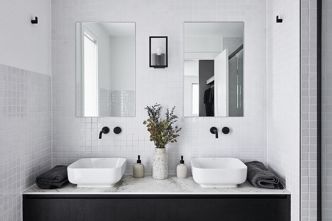 A modern double ensuite bathroom in monochromatic décor with white subway tiles, black fittings and woodwork