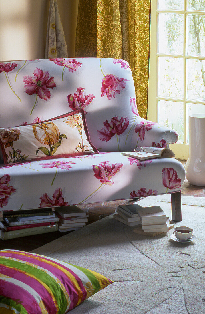 A sofa with a floral print with books underneath