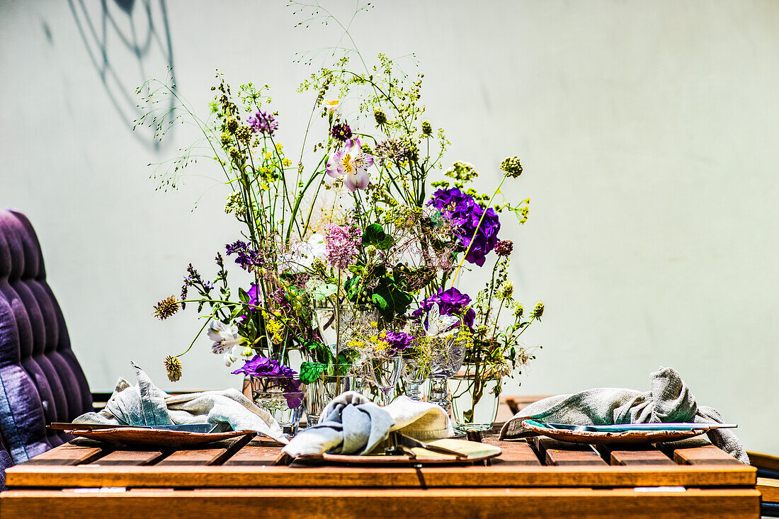 Gedeckter Tisch auf der mit Wildblumen geschmückten Sommerterrasse