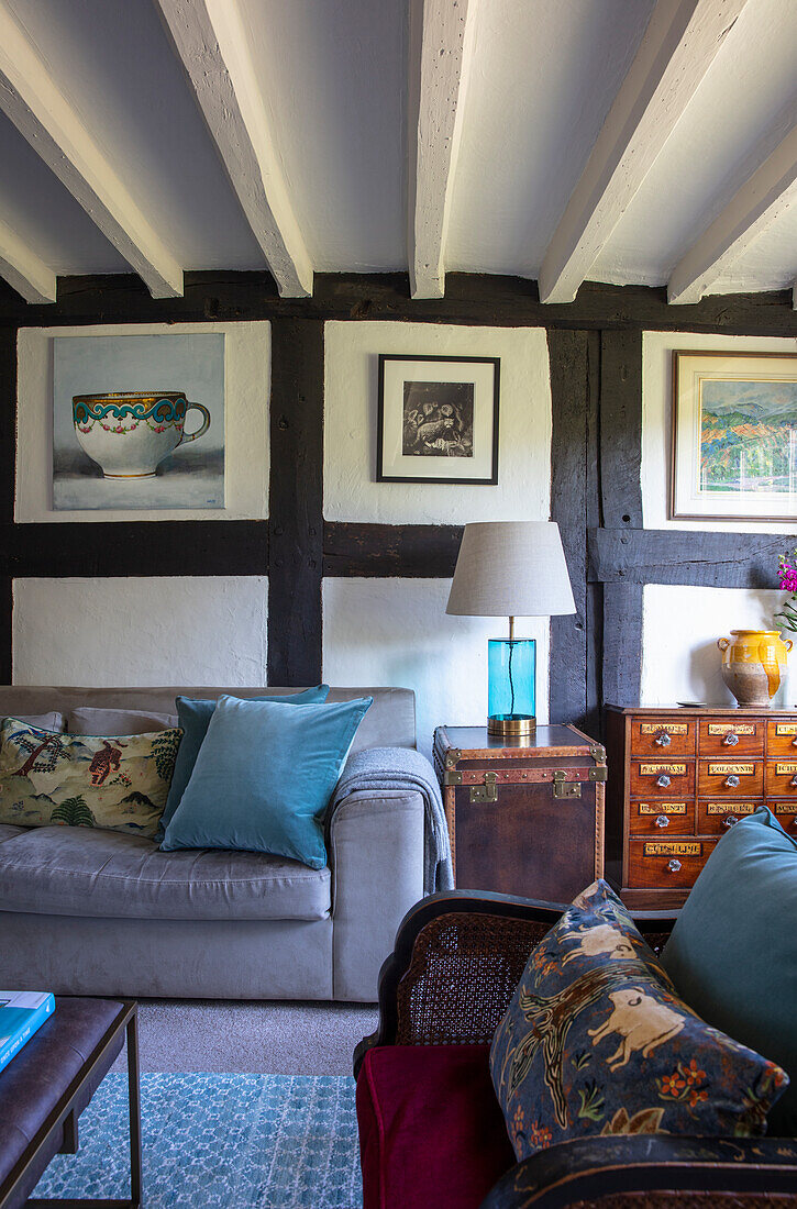 Paintings above sofa and antique furniture in a living room with timbered framed wall