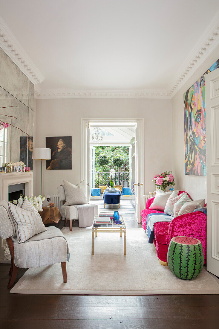 Pinkfarbenes Sofa und helle Polstersessel im Wohnzimmer mit Kamin