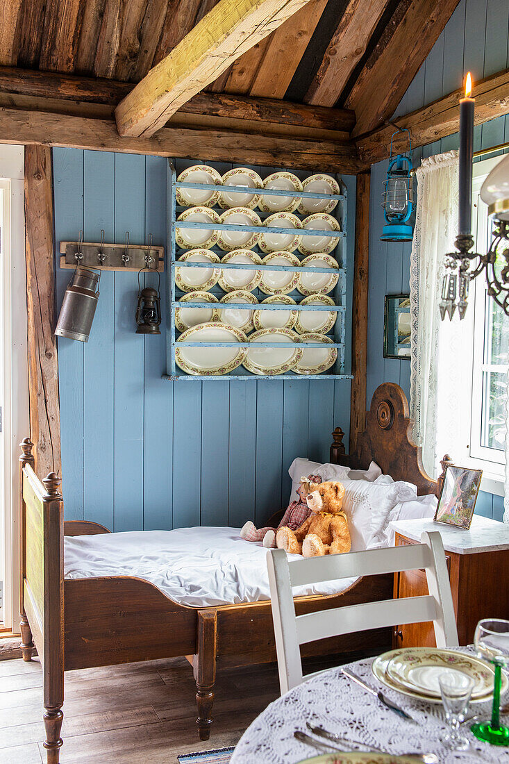 Wall mounted plate display on blue wall above children's bed in a cottage