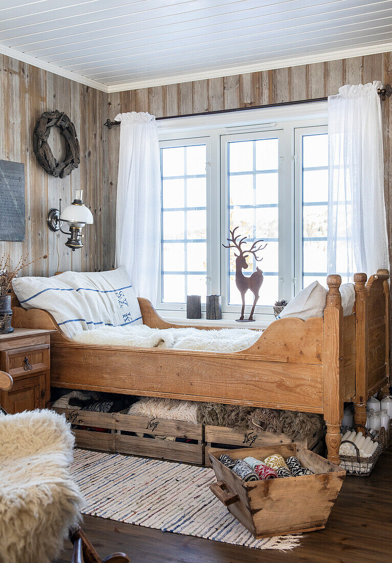Farmhouse bed, crates used as storage underneath in a bedroom with wooden paneling