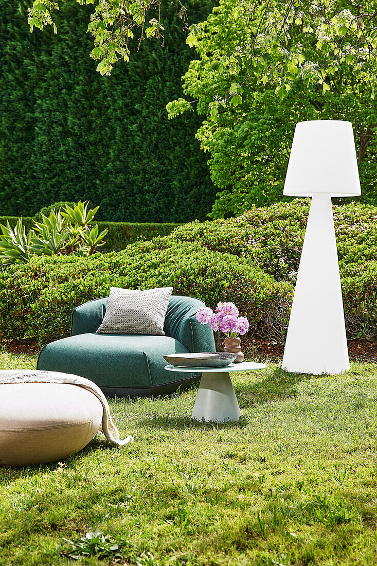 Comfortable armchair, side table and designer lamp in the garden