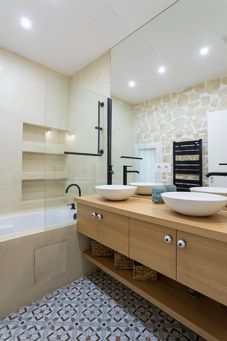 Bathroom vanity with double sinks and bathtub in light bathroom with cement tiles