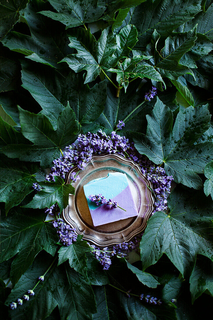 Lavender mint soap on silver tray surrounded by flowers and leaves