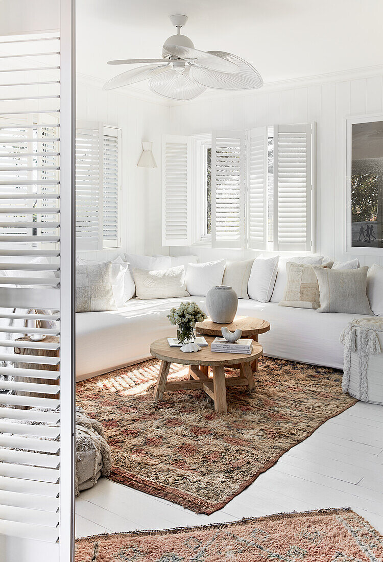 White seating furniture with linen cover, shutters and Moroccan carpets in the living room
