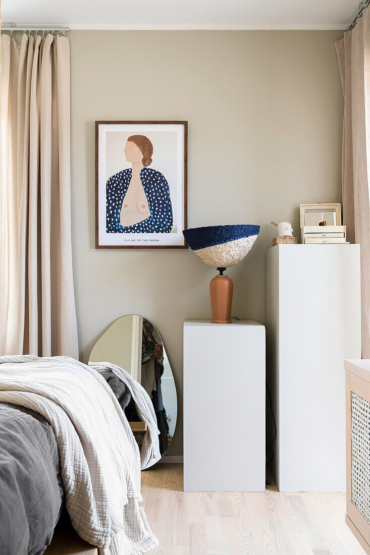 Stelen und Kunstdruck im Schlafzimmer mit sandfarbener Wand